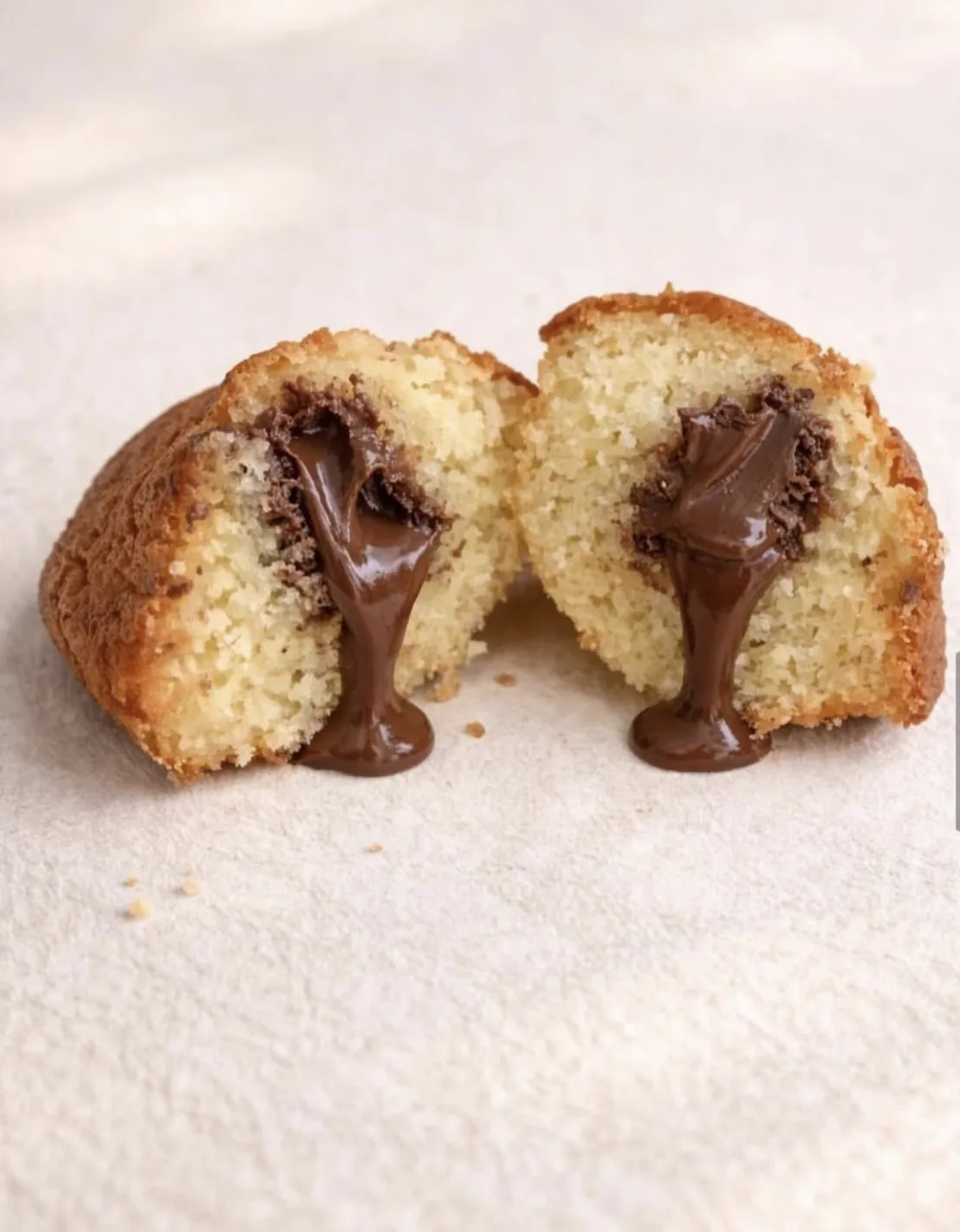 A madeleine broken in half, chocolate filling running from the centre.